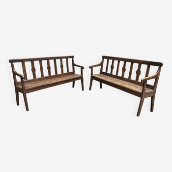 Duo of old solid oak benches with backs and armrests.