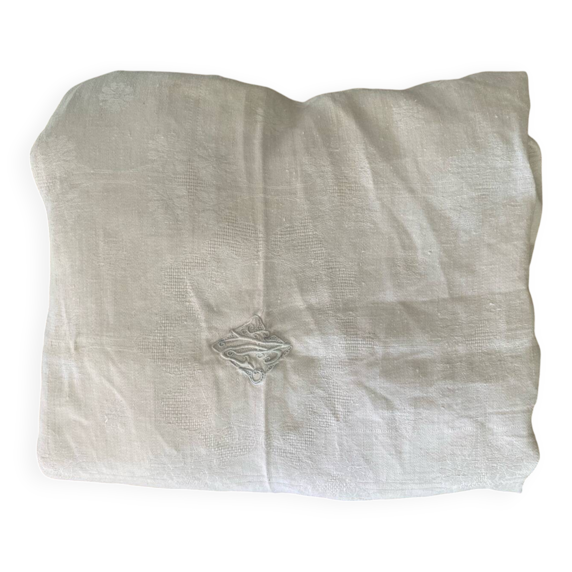 Damask tablecloth with a floral pattern and a central embroidered monogram.