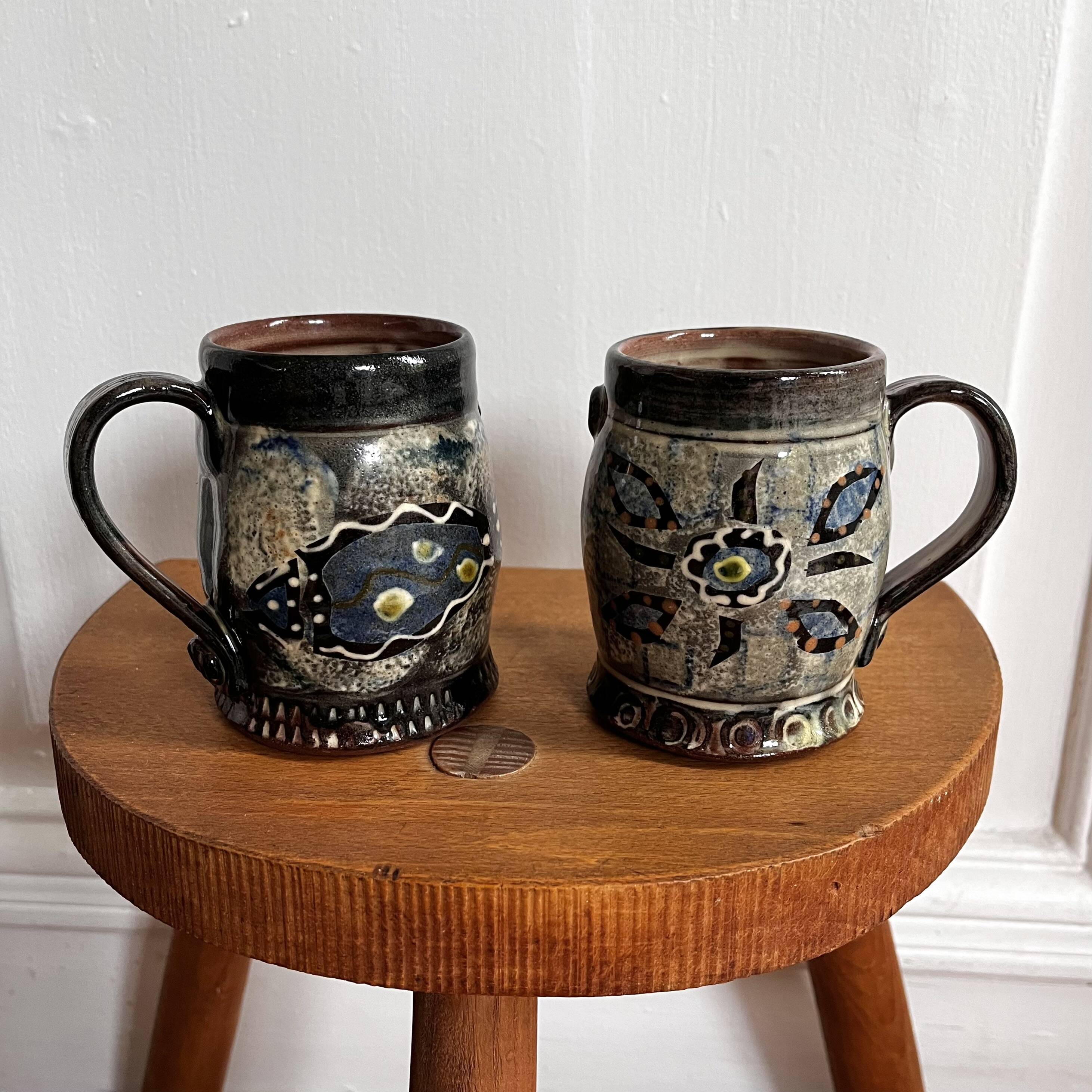 Vintage terracotta mugs with glazed designs and flower/fish motifs