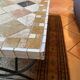 Beige ceramic coffee table with black metal legs.