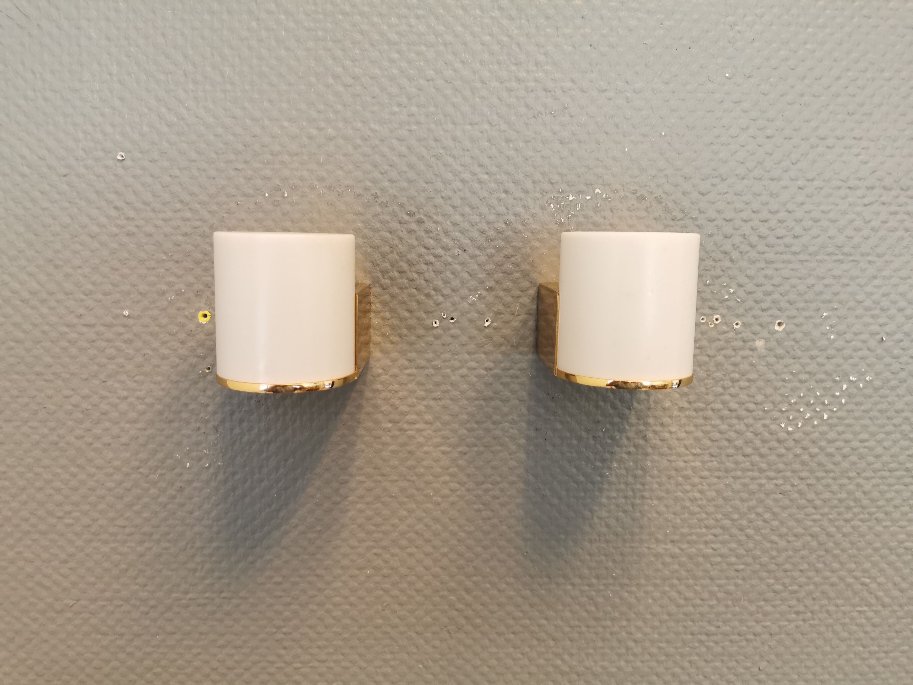 Wall lamps with milky white acrylic plastic shades and solid brass bases