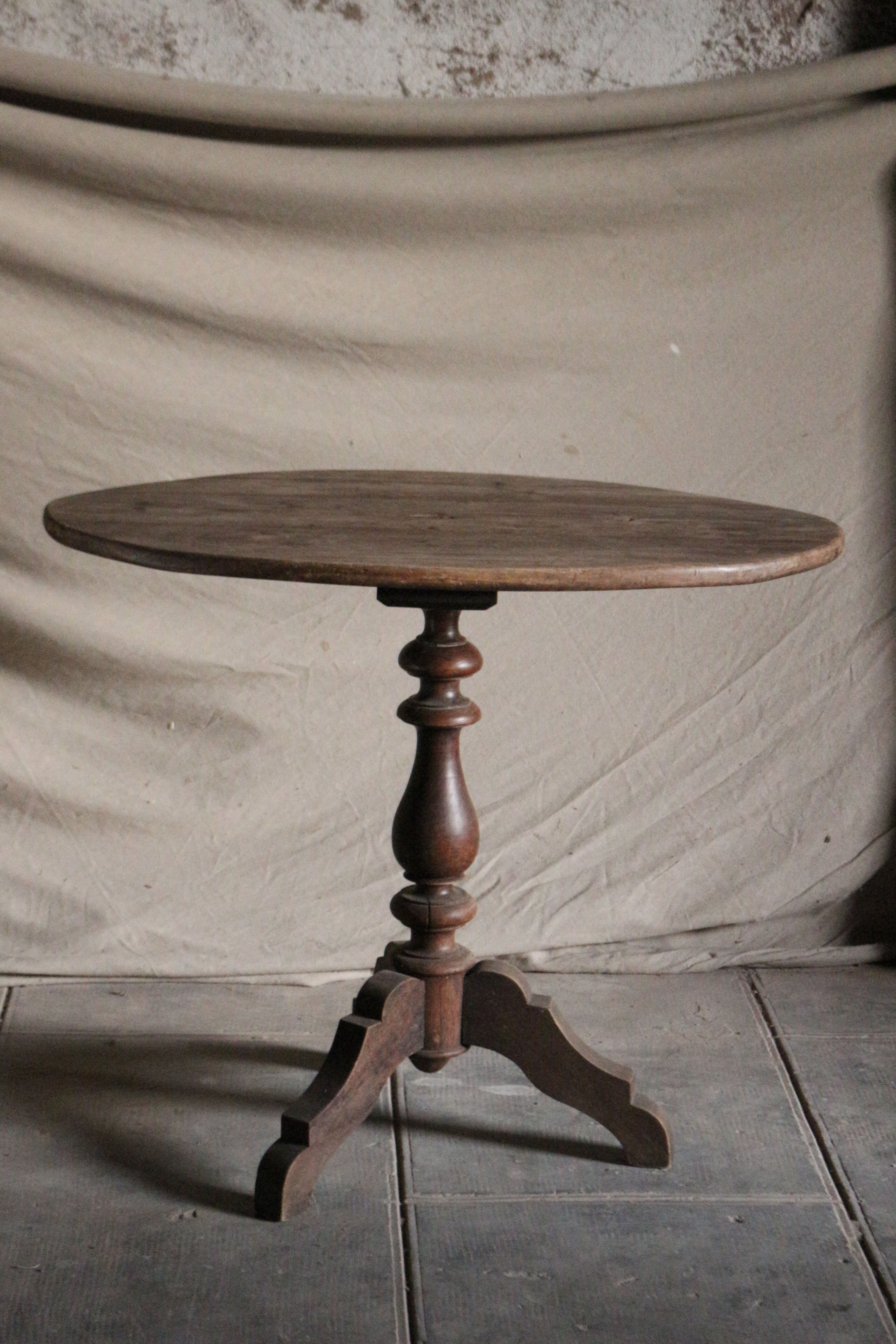 Old oval pedestal table in raw wood