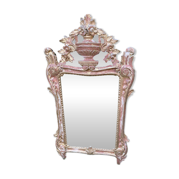 Mirror above a wooden and gilded stucco fireplace in the style of the 18th century.