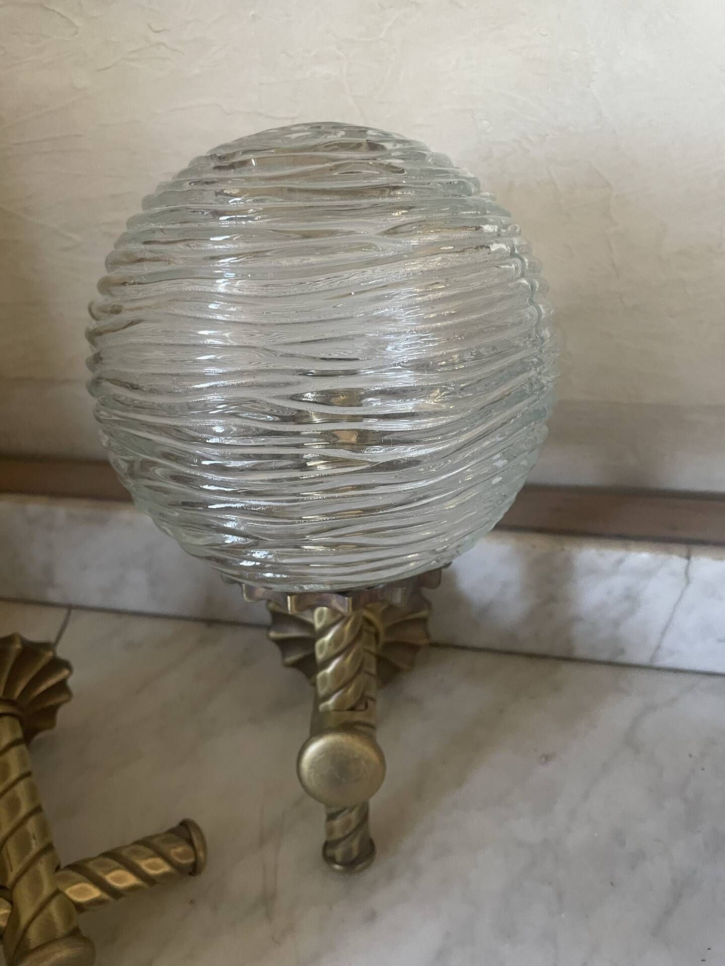 Pair of neoclassical wall sconces in twisted brass and ribbed glass.