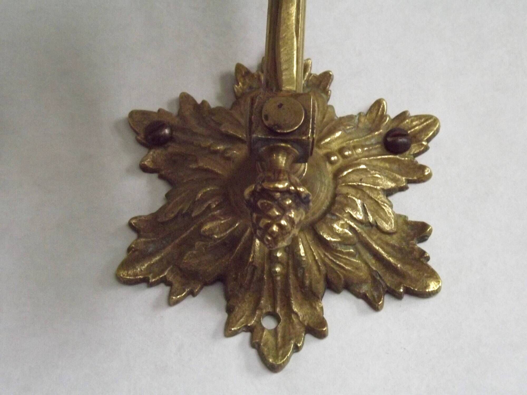 Simple wall sconce in French Art Nouveau bronze with a white glass shade featuring patterns.