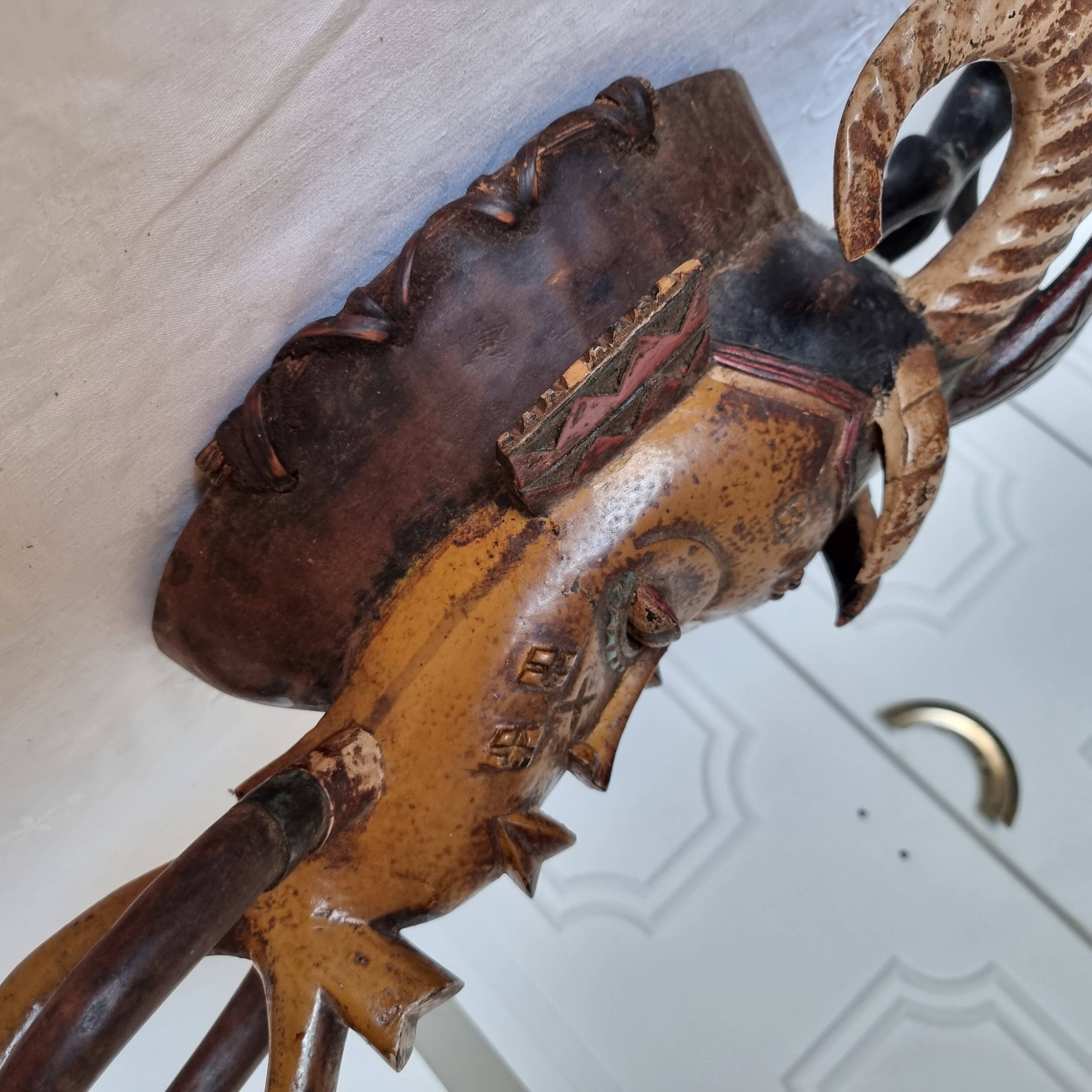 A large Senufo mask made of colored wood, decorated with an anthropomorphic figure