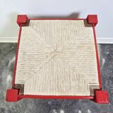 Red wooden stool with woven rush seat.
