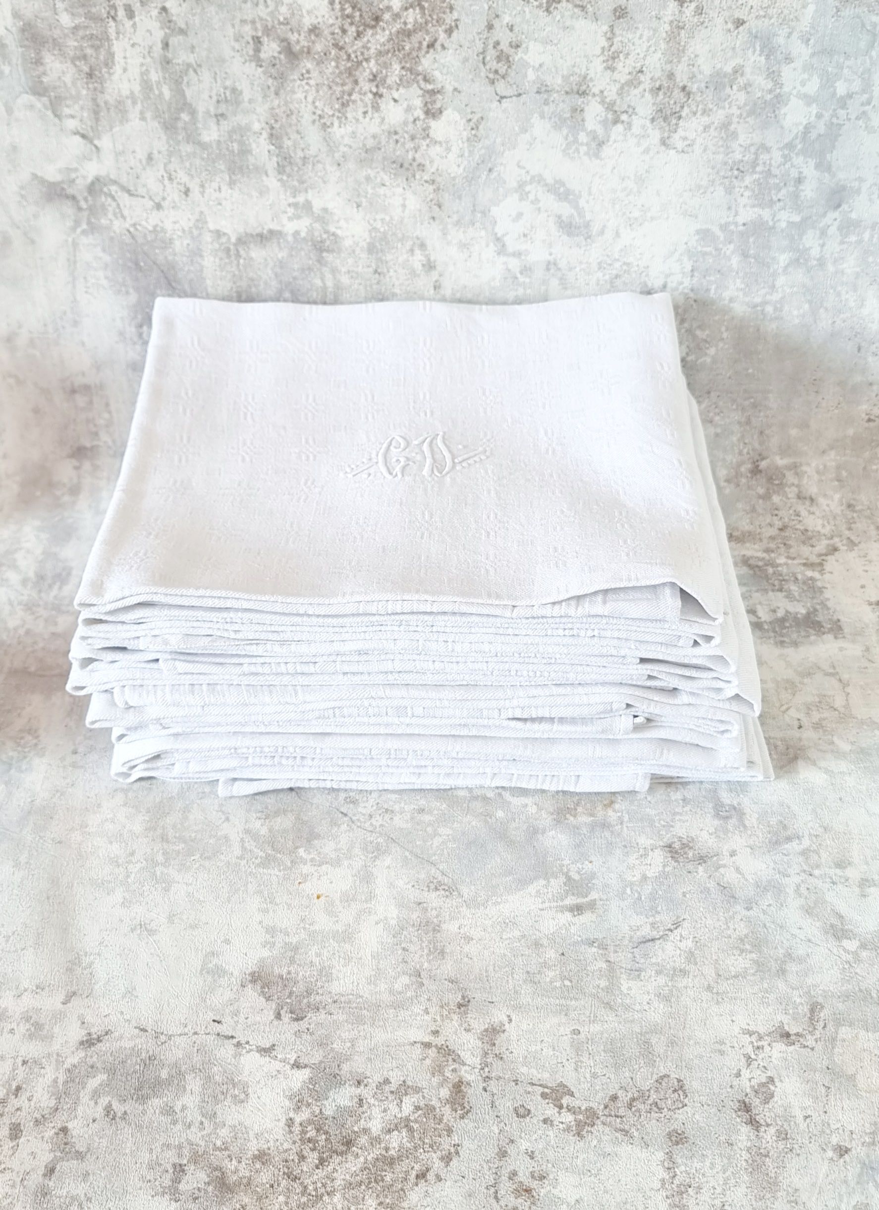 12 antique French linen towels with damask embroidery with "GB" anagrams.