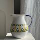 Large white terracotta carafe with a stylized green and yellow frieze pattern
