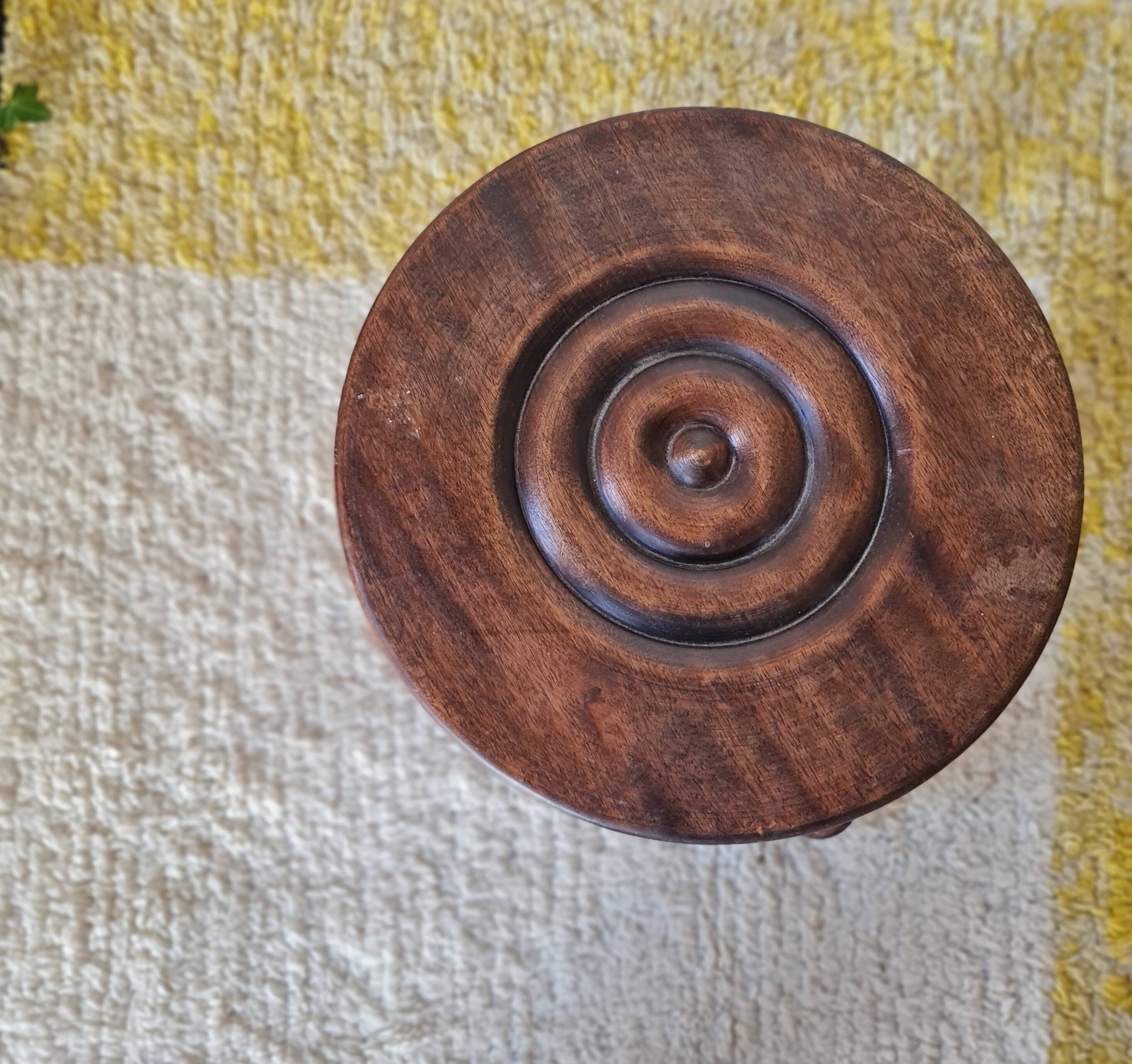Small brutalist tripod stool made of turned wood.