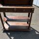Carved wooden console table with three shelves and drop-leaf flap