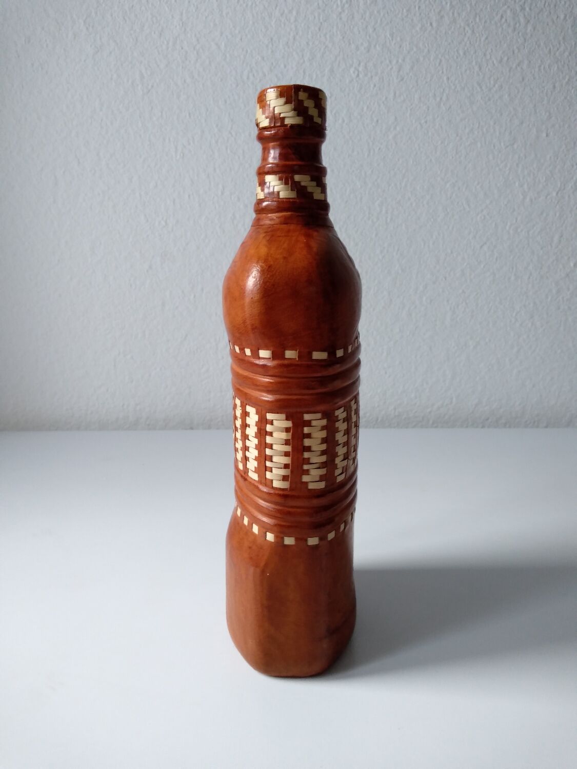 Vintage glass bottle covered with light brown leather and wicker
