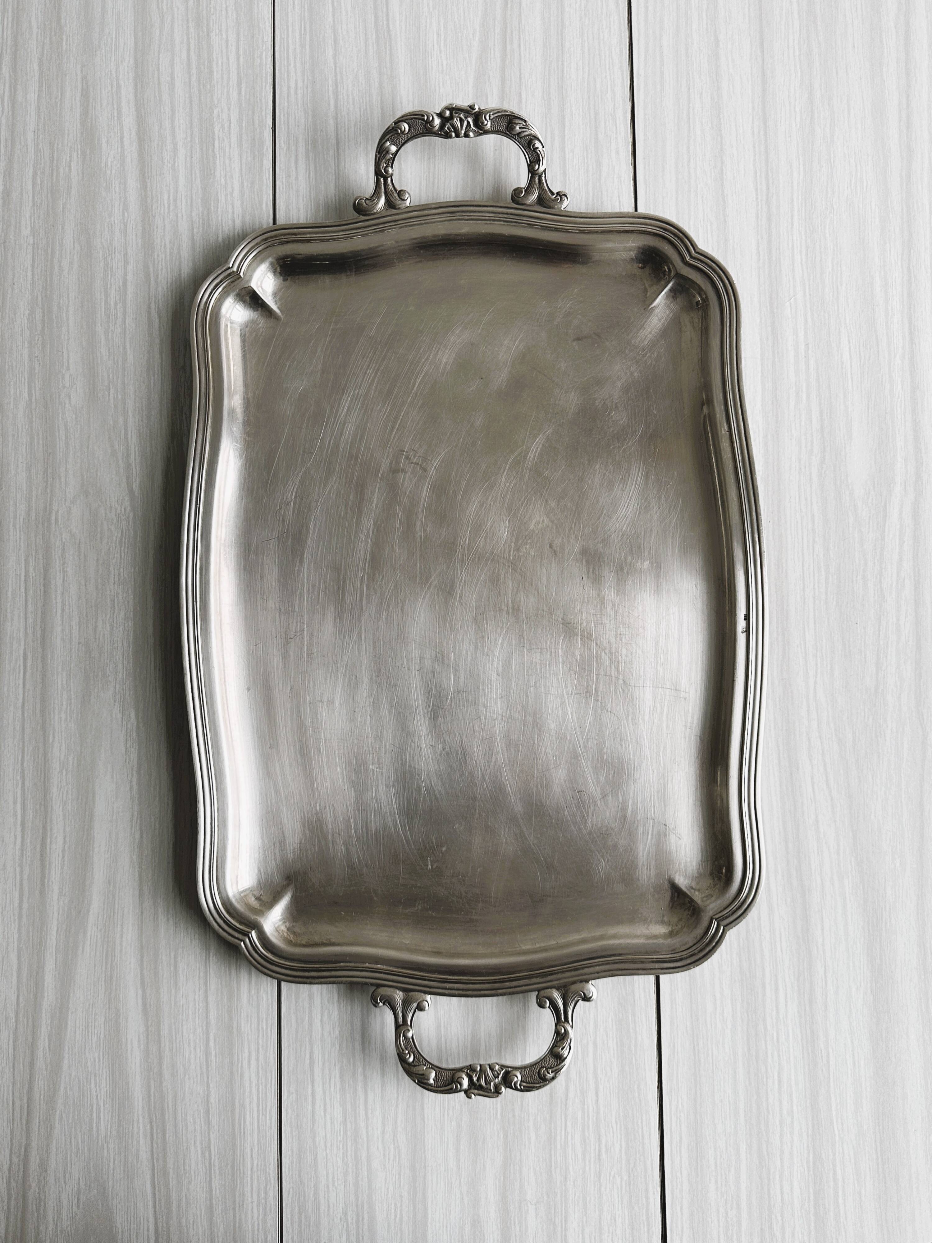 Silver metal serving tray with sculpted handles