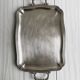 Silver metal serving tray with sculpted handles
