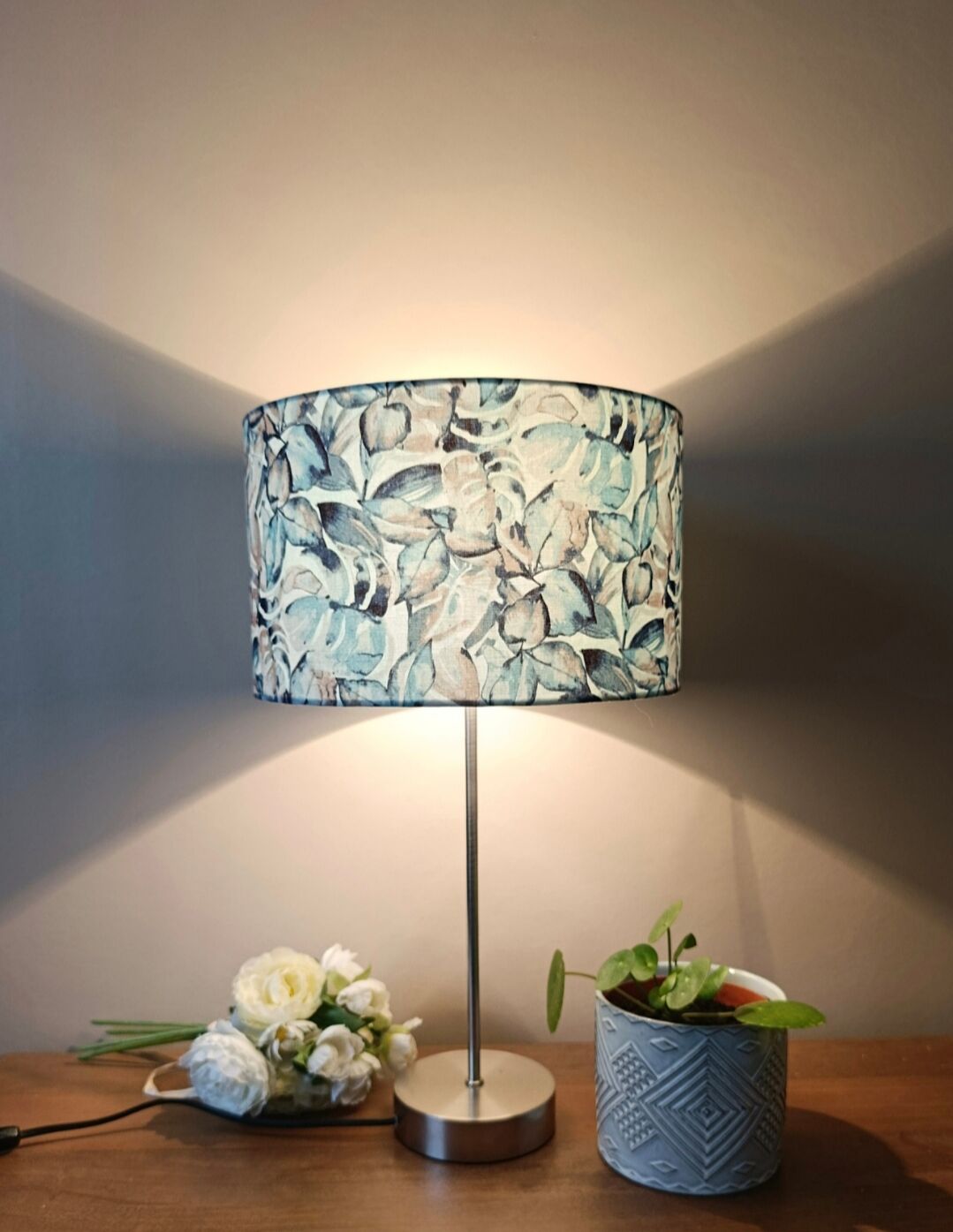 Table lamp with chrome stem, tropical plant shade.
