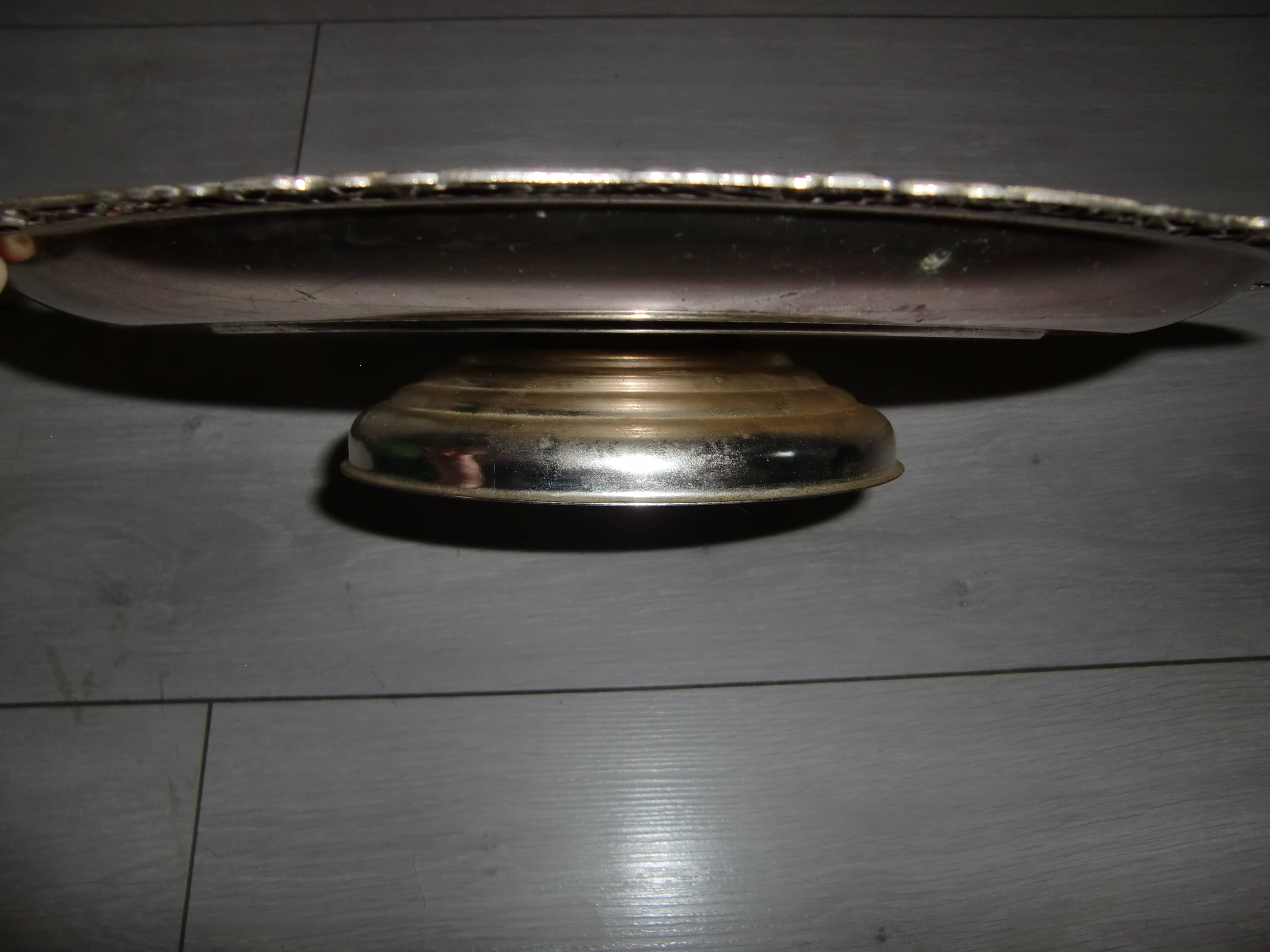 Large silver metal tray raised by a central foot