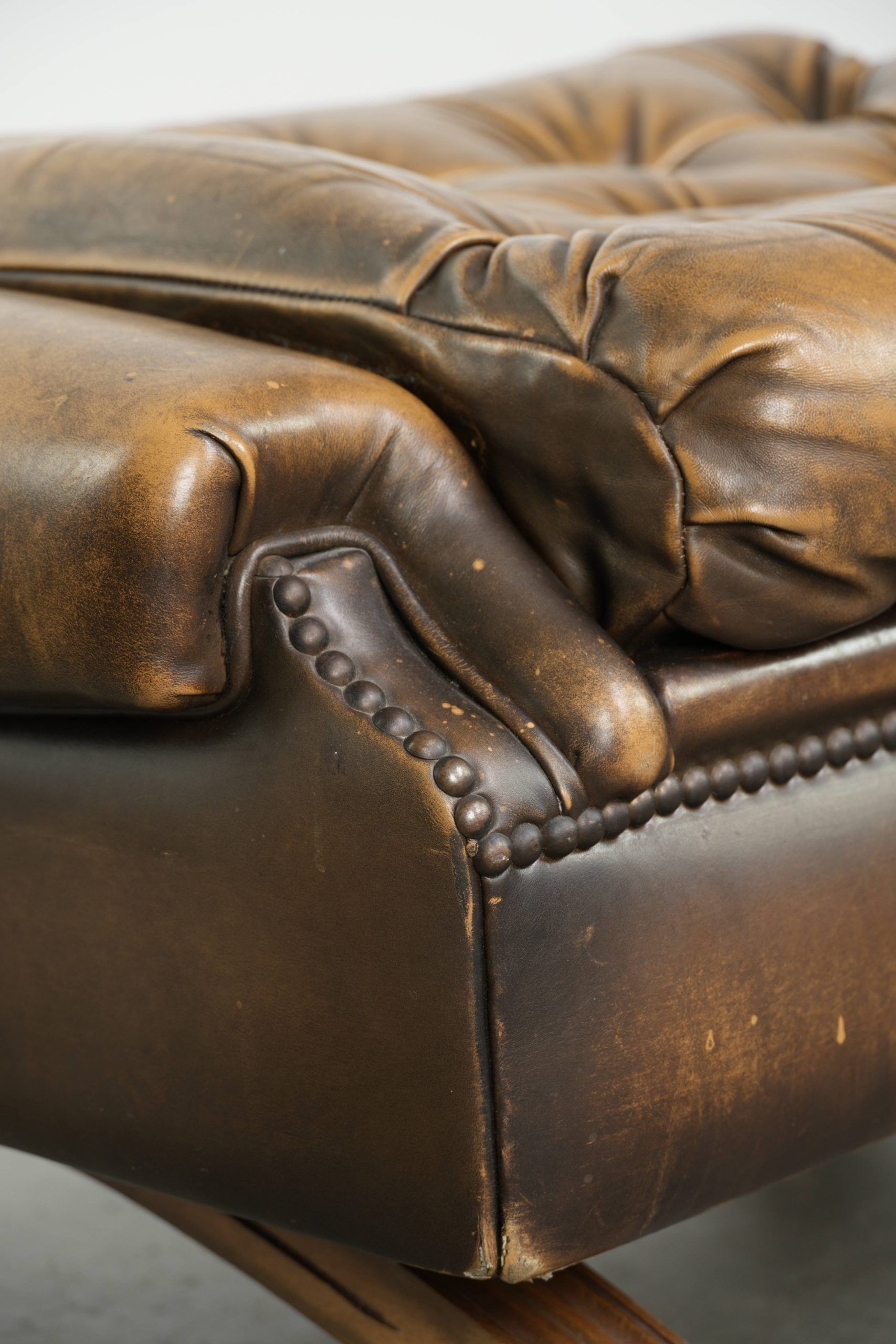 Ottoman chesterfield anglais en cuir élégant, fini avec des clous décoratifs.