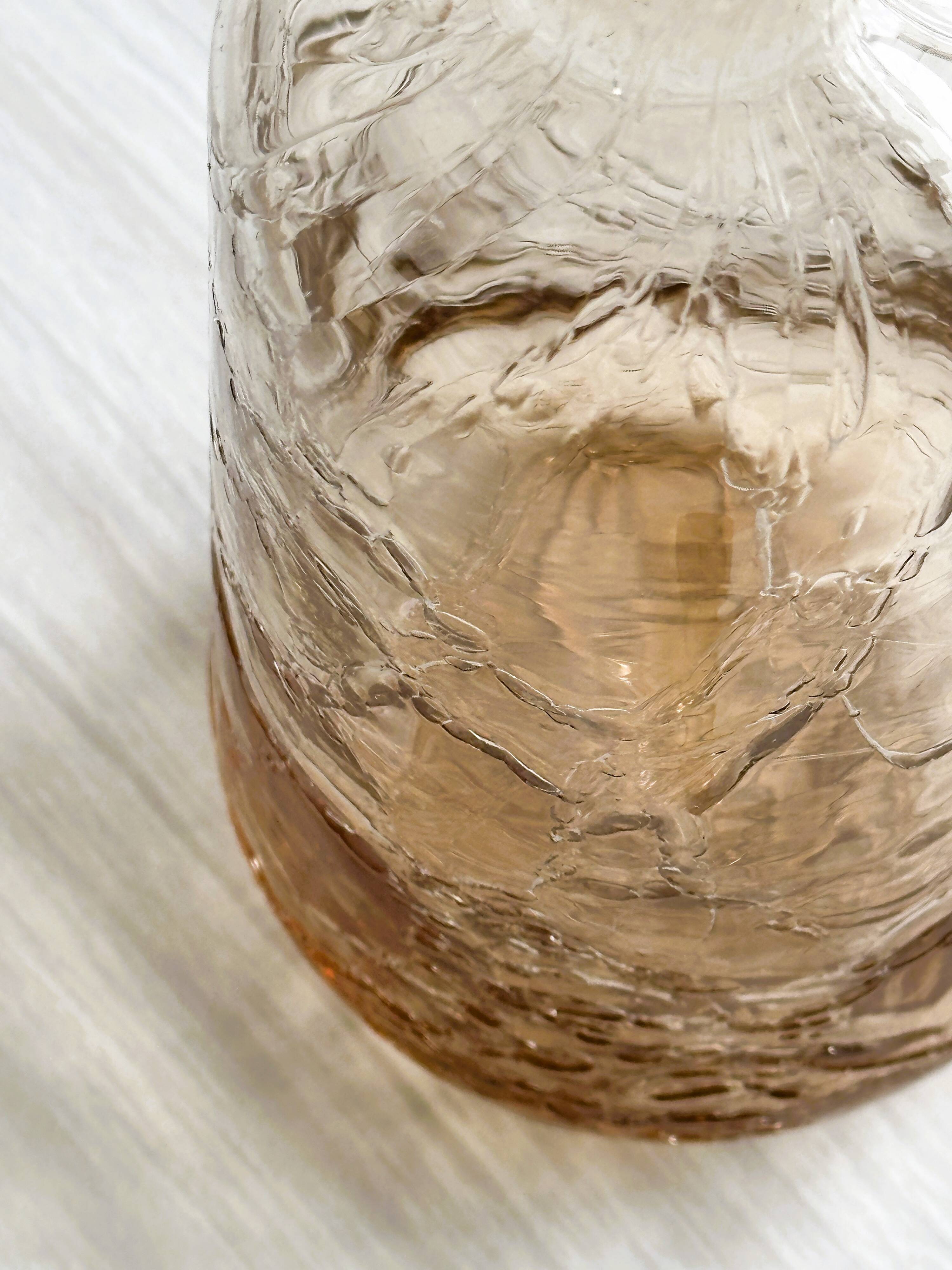 Translucent pinkish iridescent cracked glass bottle.