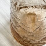 Translucent pinkish iridescent cracked glass bottle.