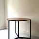Modernist round folding dining table in wood and metal.