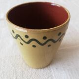 Mustard-colored ceramic cup or glass with green decor