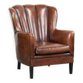 Fauteuil en peau de mouton confortable au design unique, fini avec un passepoil noir.