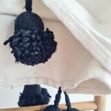 Handwoven throw with black stripes and pom-poms