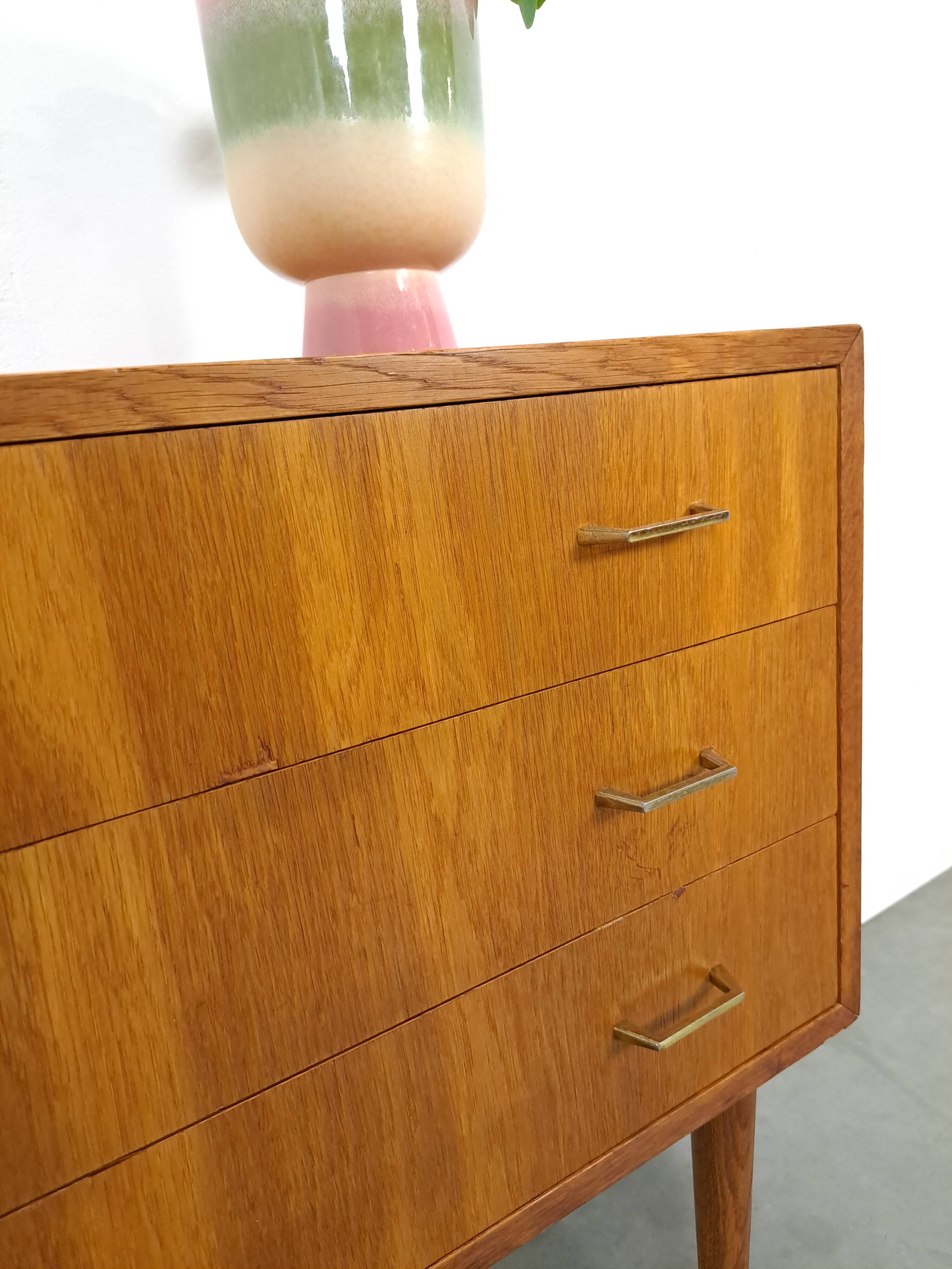 Commode danoise avec de hauts pieds et des poignées dorées.