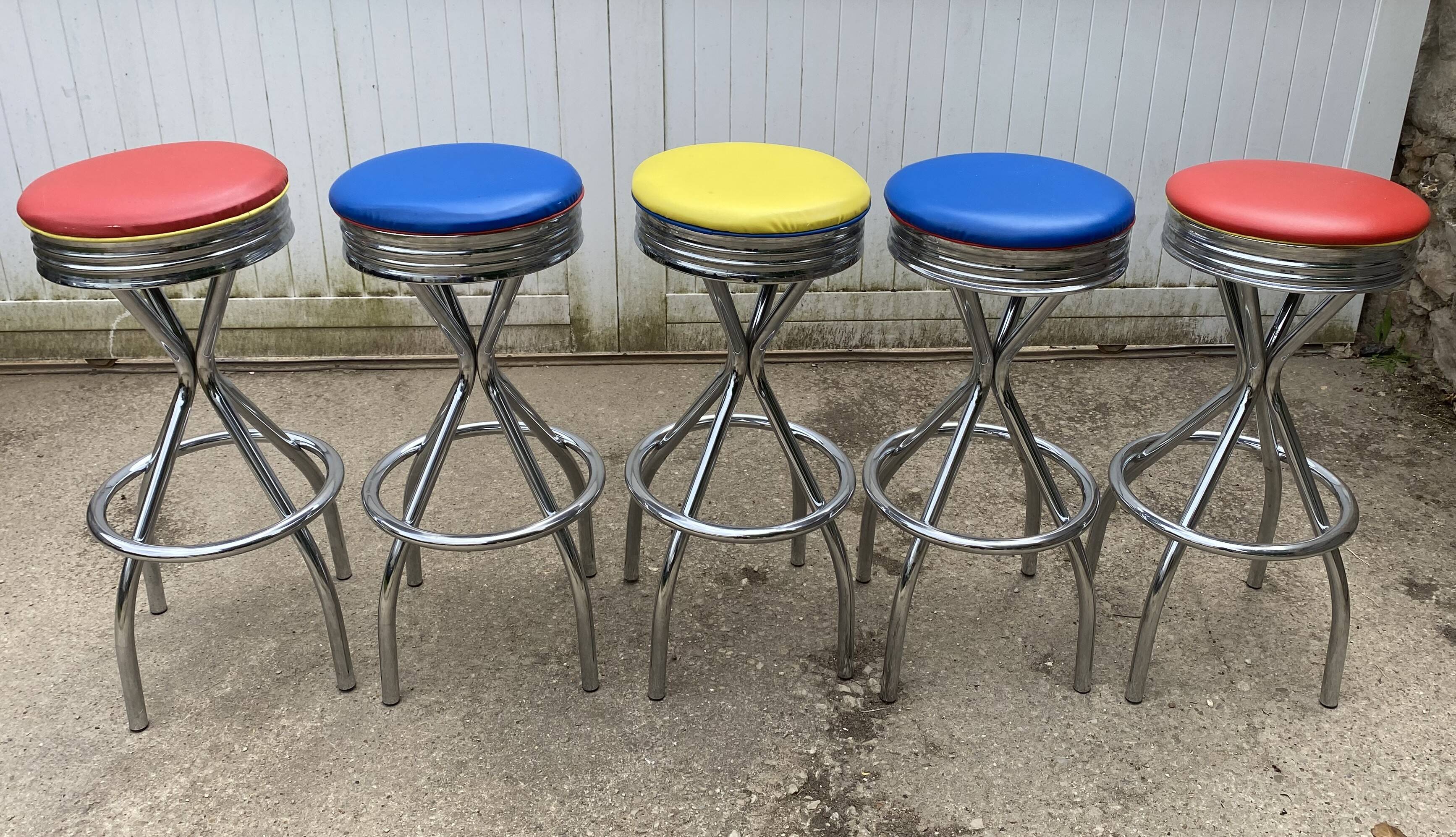 Set of 5 vintage swivel bar stools in blue, red, orange, and yellow.
