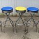 Set of 5 vintage swivel bar stools in blue, red, orange, and yellow.