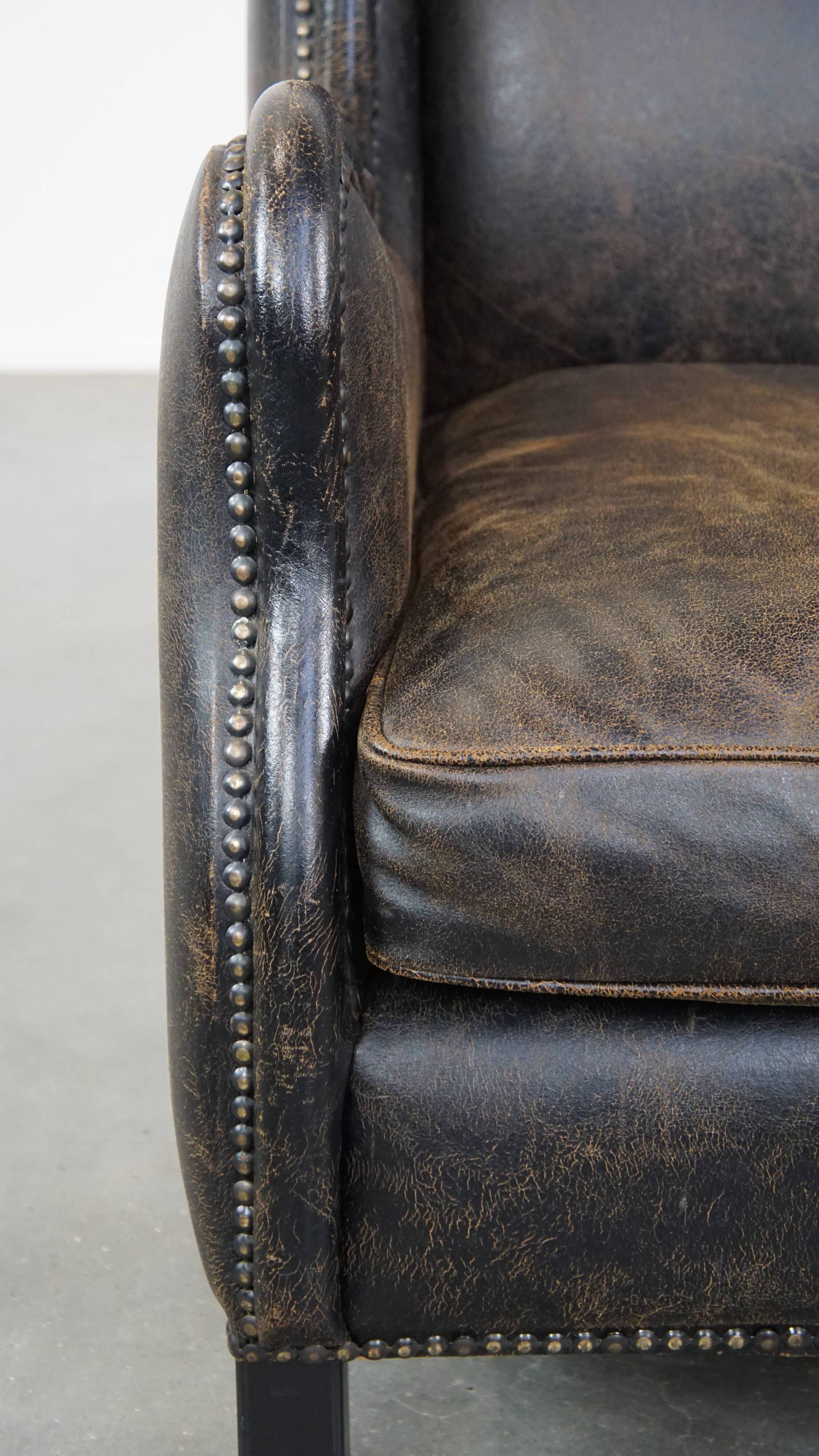 Black cow leather armchair finished with decorative nails, industrial style