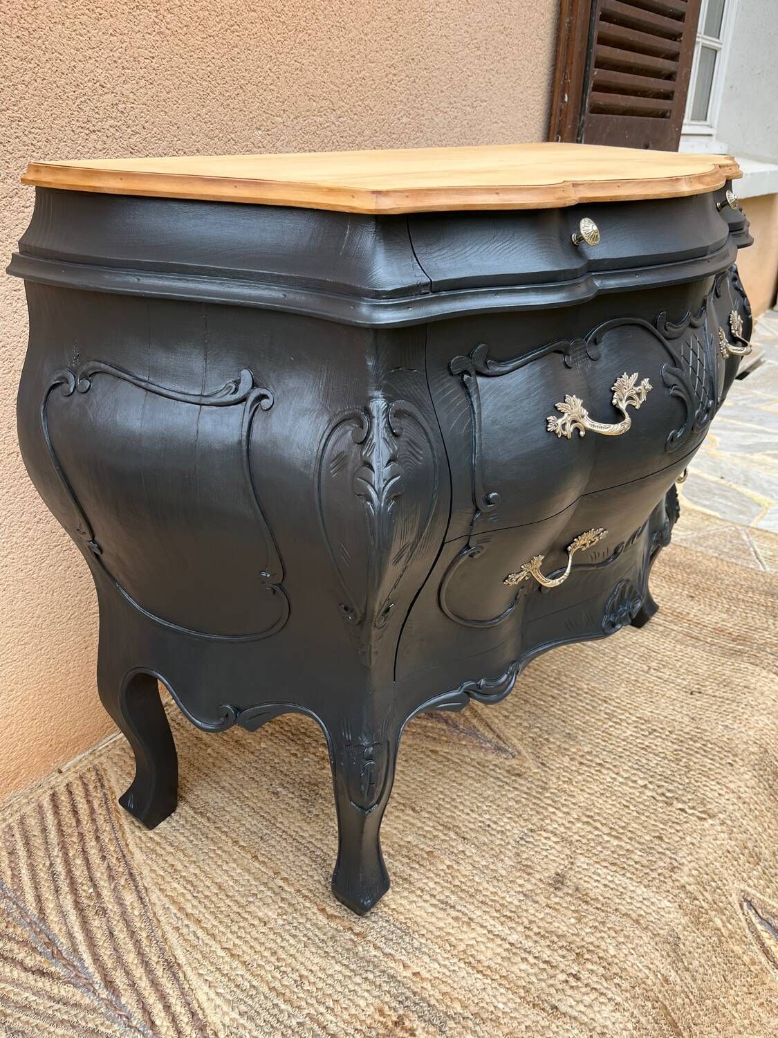 Curved commode painted in black and wood.