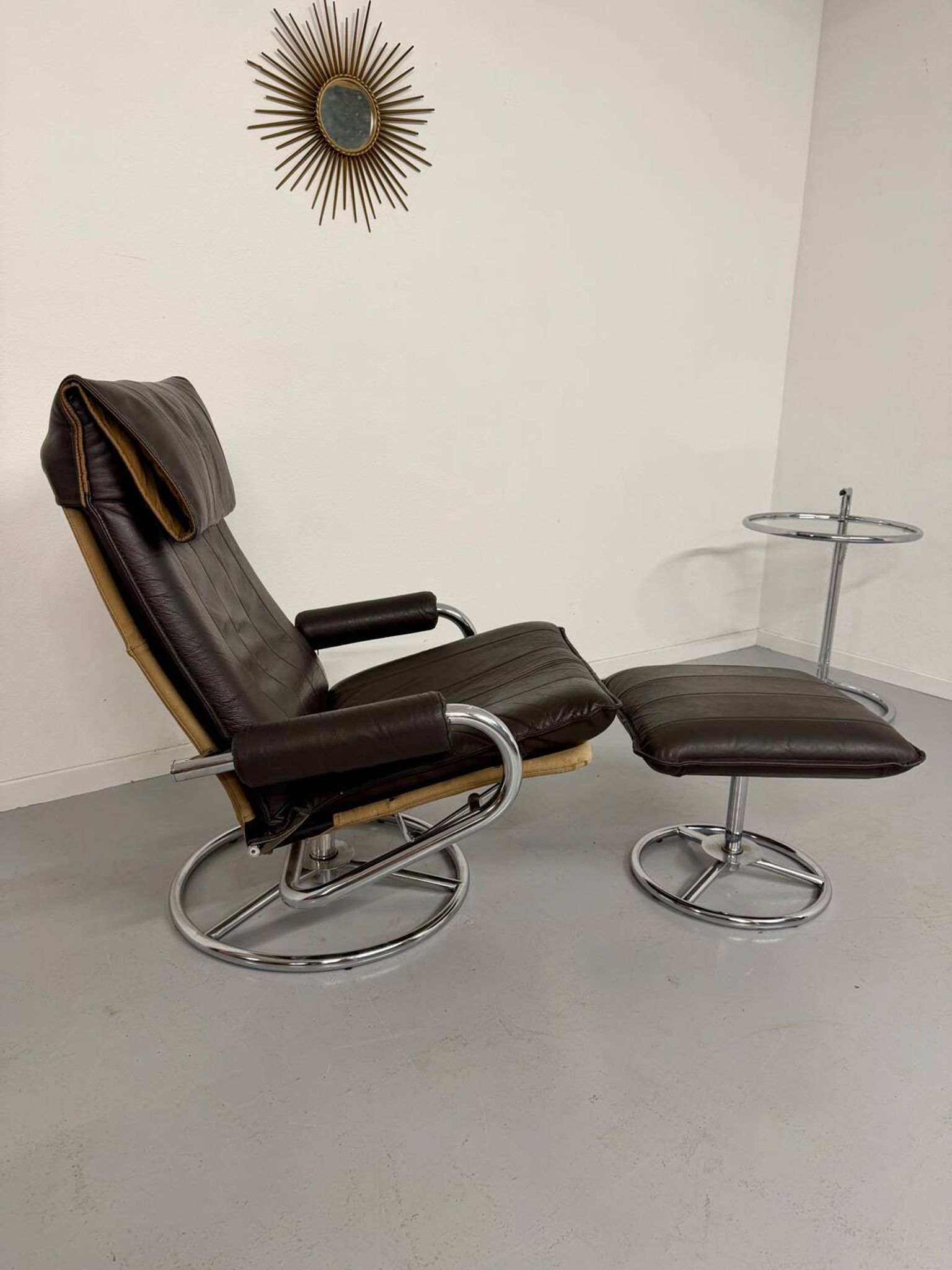 Vintage leather reclining armchair and its 1970s designer ottoman.