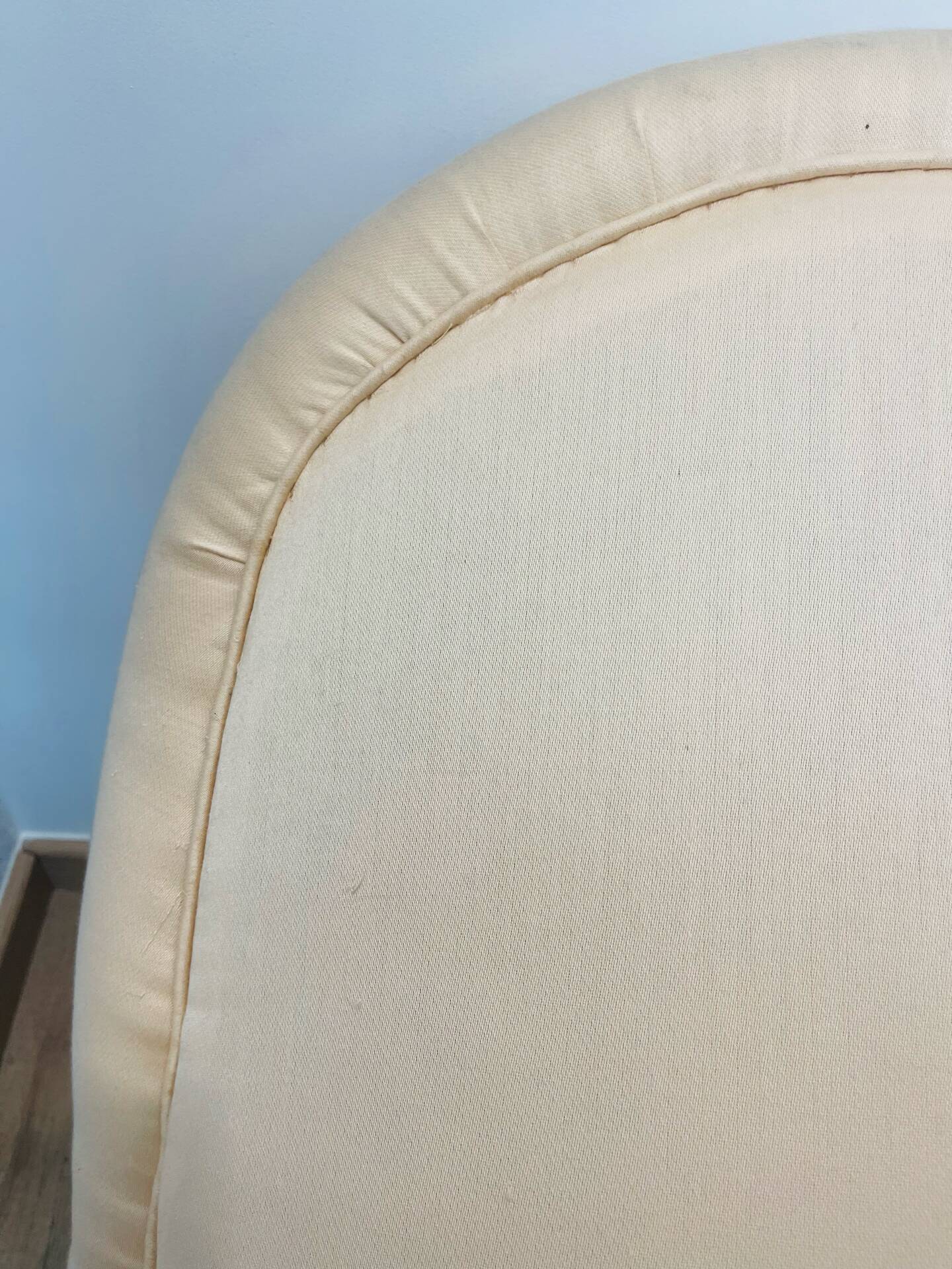 Pale pink upholstered armchair with wooden legs.
