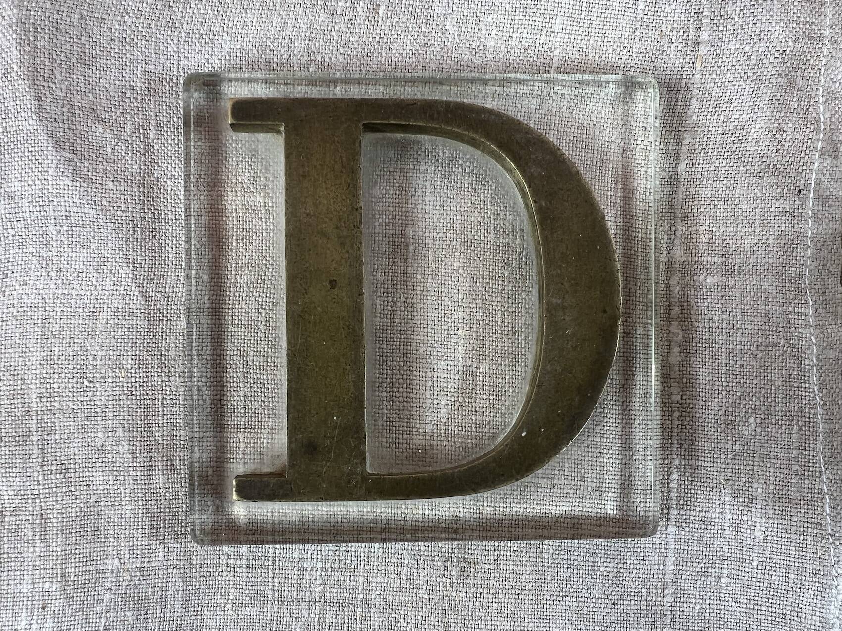 Metal letter D on glass plate