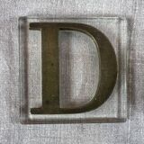 Metal letter D on glass plate