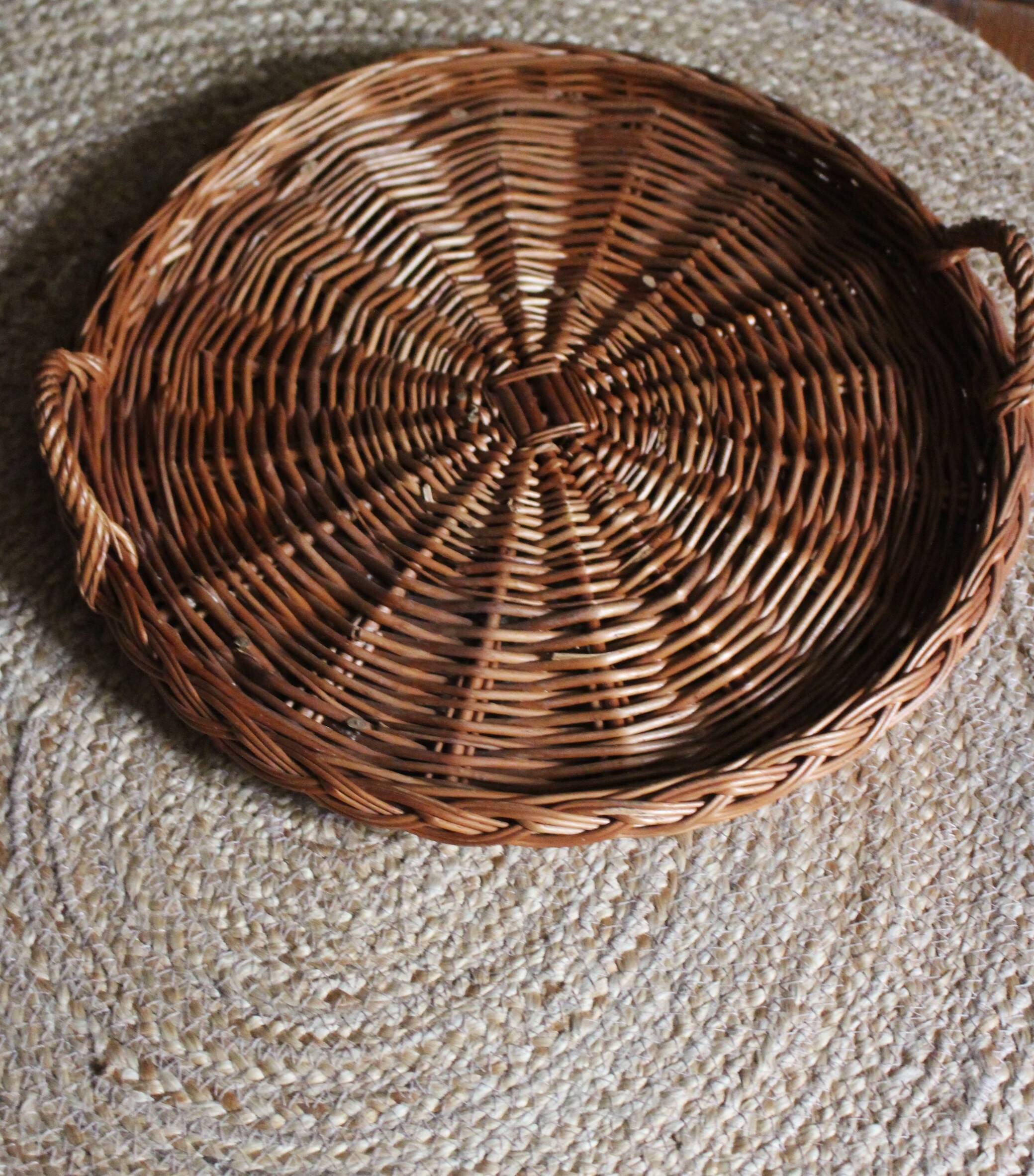 Large round dark wicker tray with two handles.