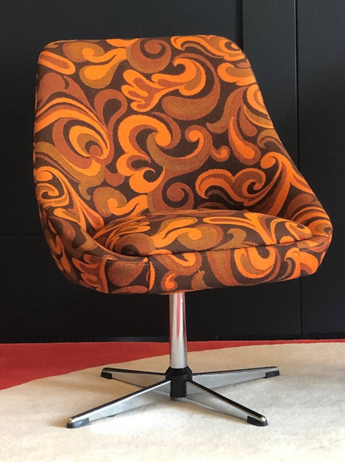 Vintage space age swivel chair with psychedelic pattern in shades of orange.