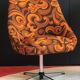 Vintage space age swivel chair with psychedelic pattern in shades of orange.