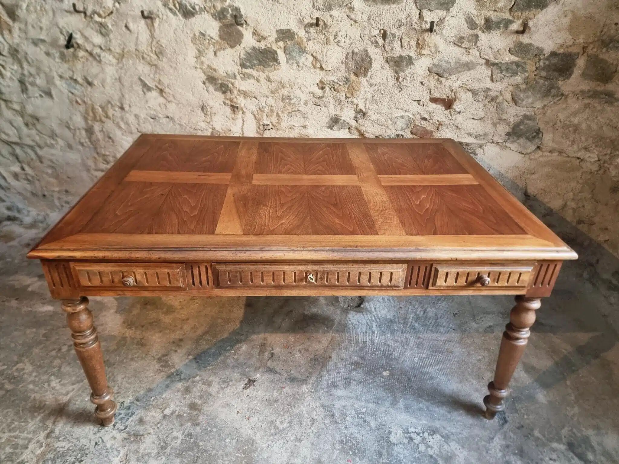 Antique French walnut table with six drawers, parquet top, early 20th century.