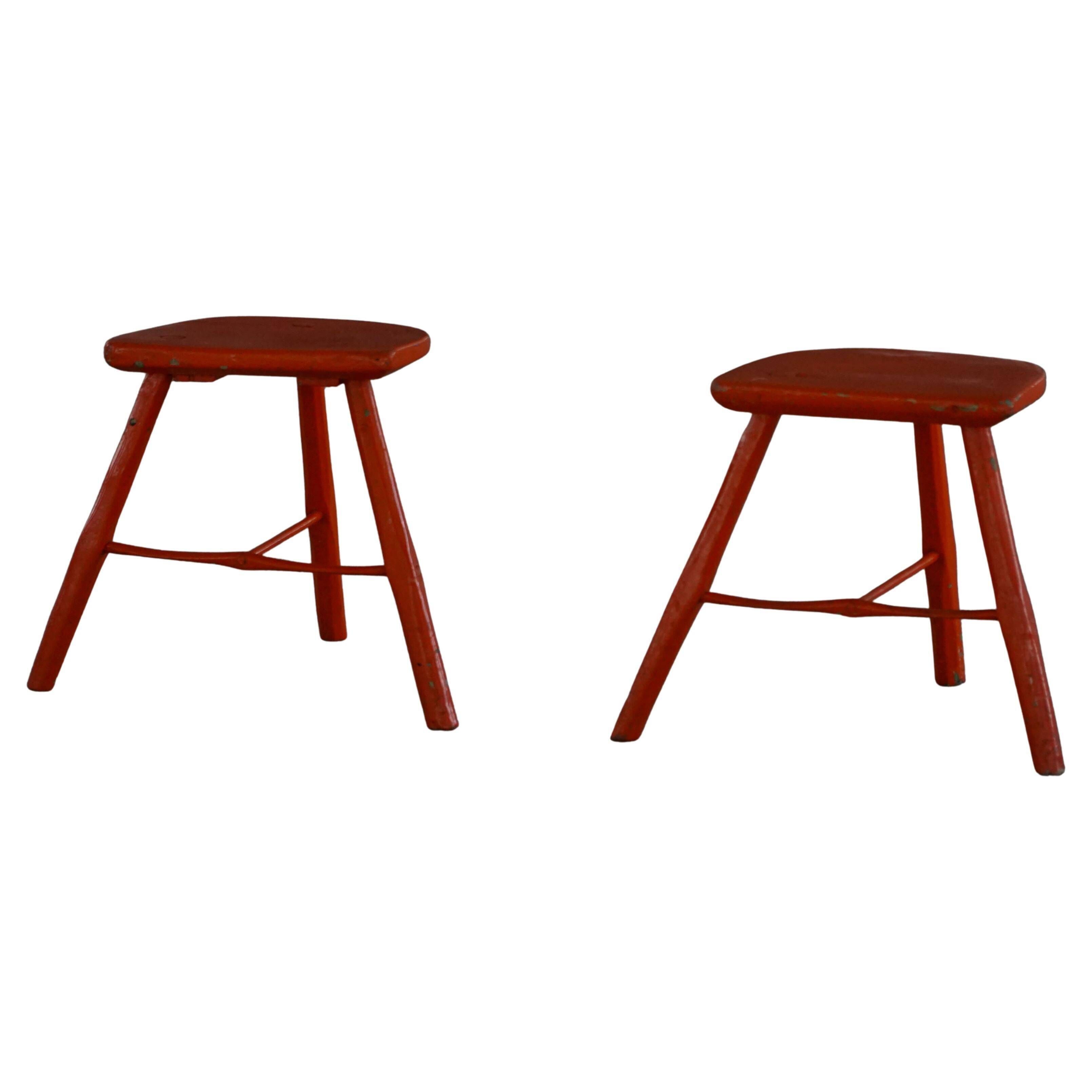 Pair of wooden stools painted in patinated red with flared legs, 1950s-1960s.