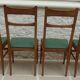 6 modern chairs with banded backs and green faux leather seats.