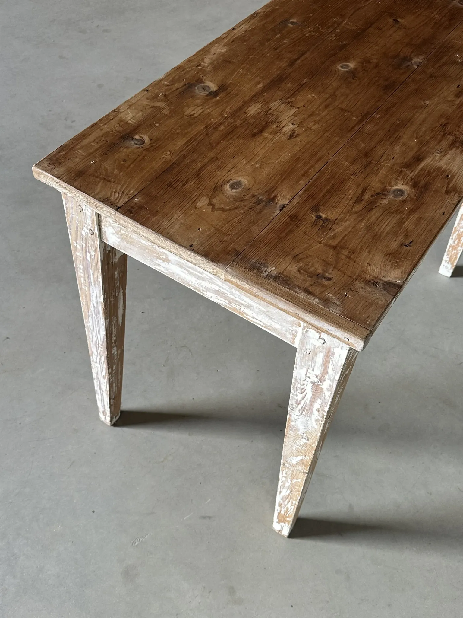 Vintage table made of raw wood with a distressed white base.