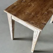 Vintage table made of raw wood with a distressed white base.