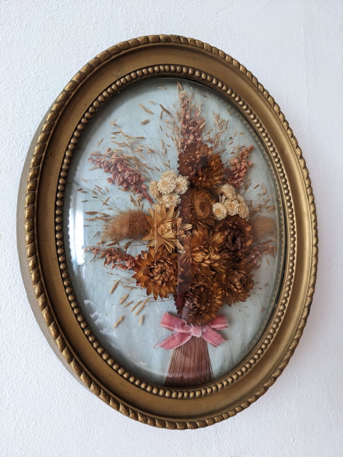 Golden vintage frame with bouquet of dried flowers under globe, wedding bouquet, antique bouquet
