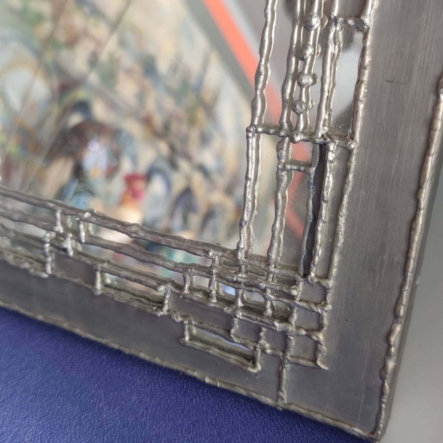 Pewter mirror on a brutalist-style wooden stand