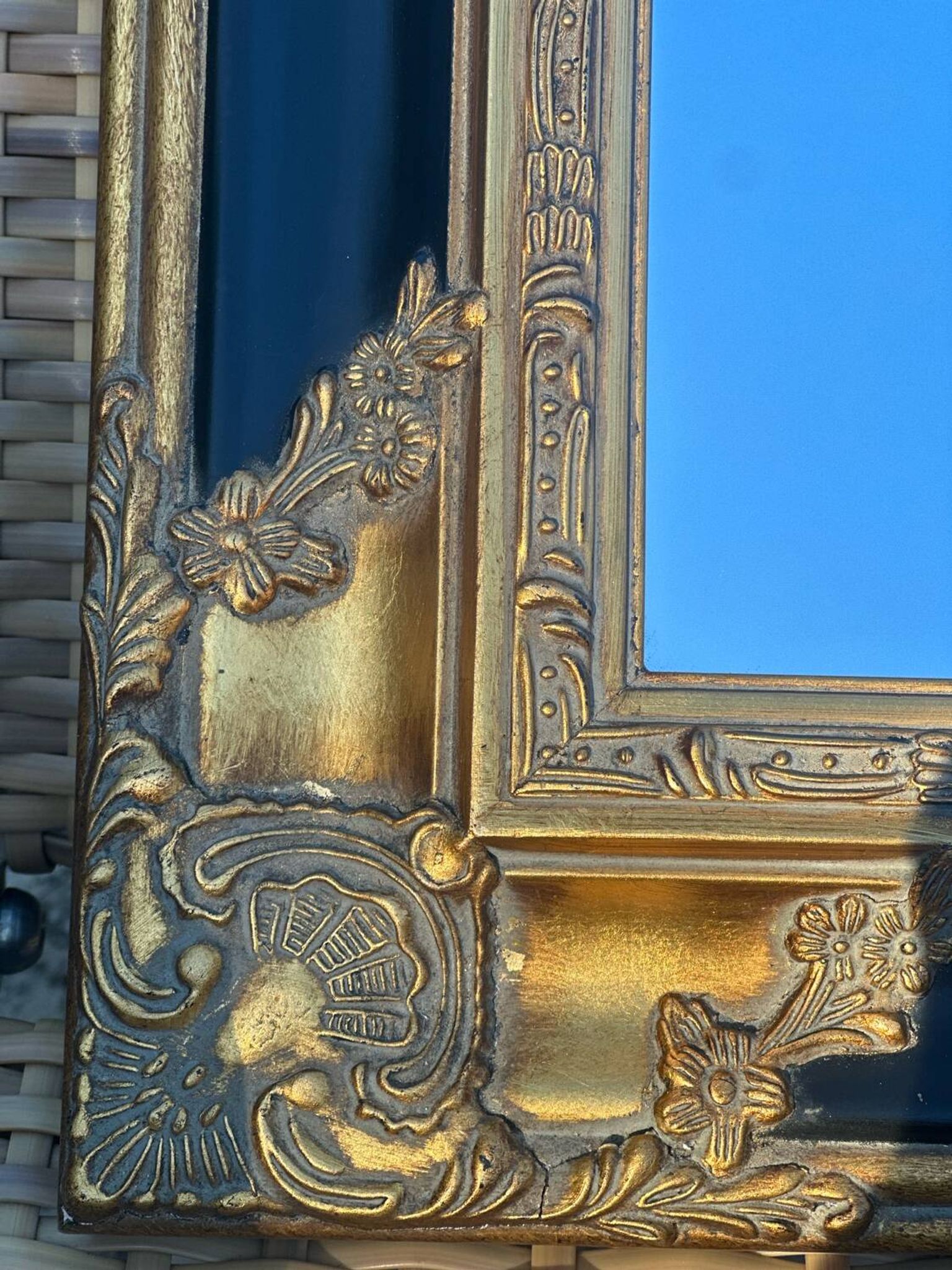 Miroir Baroque en bois doré sur fond noir.
