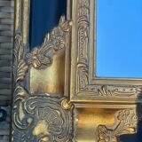 Baroque mirror in gilded wood on a black background.