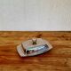 Vintage silver-plated metal butter dish with a gold tassel knob