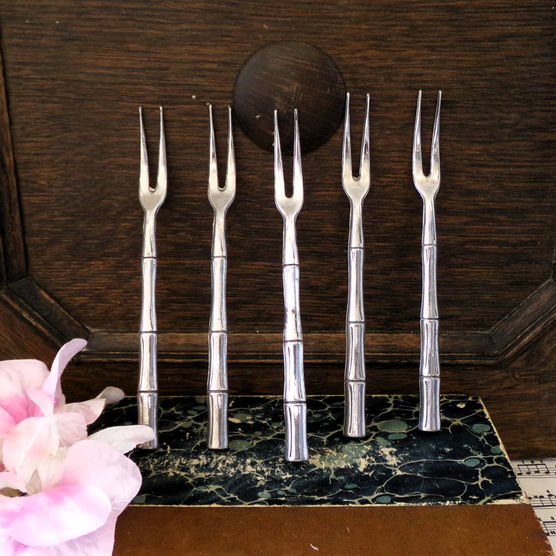 Five silver-plated metal appetizer forks with bamboo-style handles